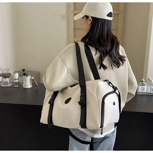Detail of a large cream travel bag featuring black nylon straps and waterproof fabric