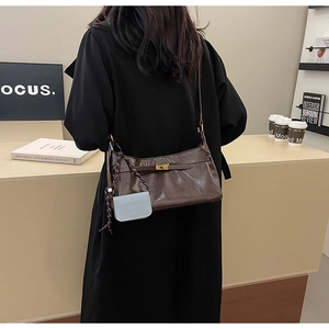 Detail of vintage brown leather shoulder bag with gold metal lock and blue charm