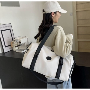 Detailed side view of white nylon travel bag with black straps on female model