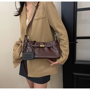 Detail of vintage dark brown faux leather shoulder bag with gold clasp and mini pouch charm
