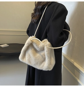 Close-up of plush faux fur shoulder bag with leather straps on a black wool coat