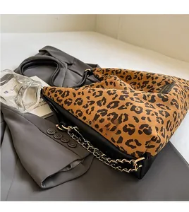 Detail of leopard print tote bag with black leather straps and gold metal chain accent