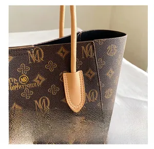 Detail showing the precise stitching and monogram pattern on the brown tote bag handle