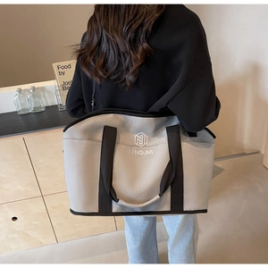 Close-up of NINGJIA logo embroidery on gray canvas tote bag with black trim and stitching