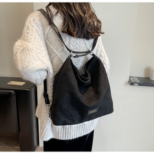 Close-up of the black matte suede tote bag showing fashion tag and spacious design