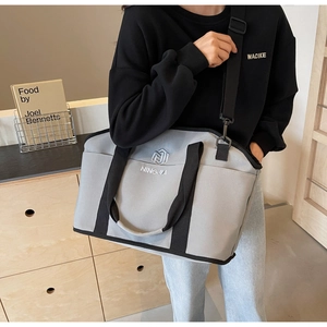 Detail of grey canvas tote bag with adjustable shoulder strap and embroidery