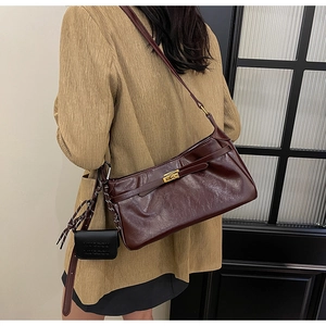 Detail view of a vintage dark reddish-brown leather shoulder bag with gold hardware