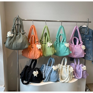 Detalle de bolsos tote acolchados de nailon de colores con un tierno colgante de oveja felpa