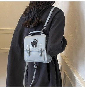 Détail du sac bandoulière bleu clair avec broderie chat et boucles en métal sur mannequin