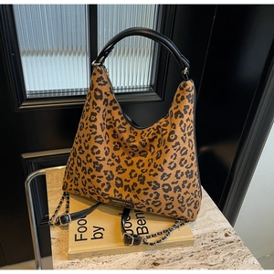 Detailed shot of leopard print tote bag with black leather handles and metal chain strap