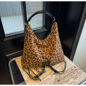 Detail of leopard print tote bag featuring weave chain strap and leather brand label