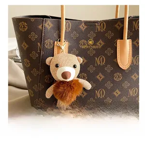 Detail of a cute knitted bear charm with a plush pom-pom on a classic tote bag