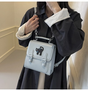 Détail du sac bandoulière bleu clair avec broderie chat noir et boucles métalliques