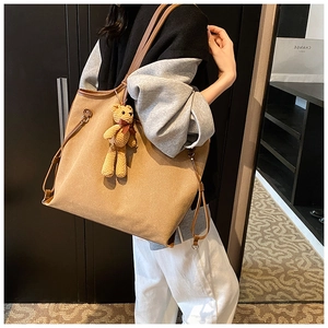 Detail of khaki canvas tote bag with brown leather trim and cute bear keychain