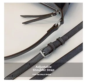Detail of adjustable gray lychee leather shoulder strap with silver metal hardware buckle