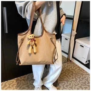 Canvas tote bag with leather trim and teddy bear charm shown in a daily life scene