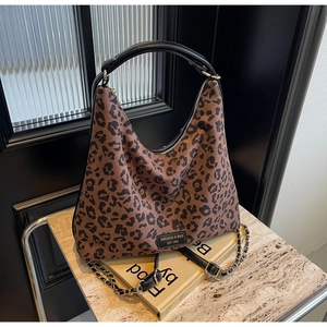 Detail of leopard print tote featuring gold chain strap and black leather handle