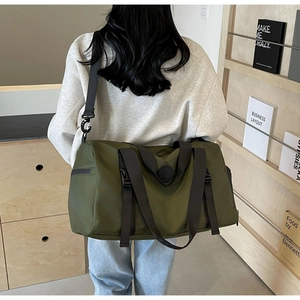 Army green nylon travel bag shown on shoulder in a lifestyle home setting