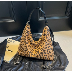 Detail of leopard print hobo bag featuring black leather handles and gold chain accents