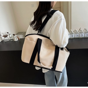 Detail of a large beige yoga travel bag with black straps and adjustable shoulder strap