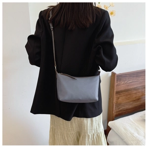 Minimalist blue nylon crossbody bag styled as a shoulder bag on a female model