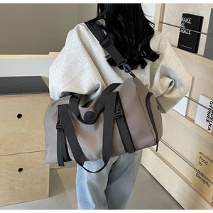 Detail of khaki fitness bag featuring a logo, durable top handles and adjustable shoulder strap