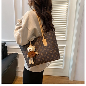 Detail of vintage brown leather tote bag with monogram pattern and plush bear charm