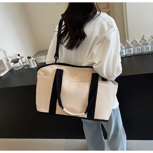 Detail of minimalist beige yoga travel bag featuring black straps and NINGJIA gold embroidery