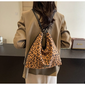 Detail of leopard print tote bag featuring black leather straps and metal chain link accents