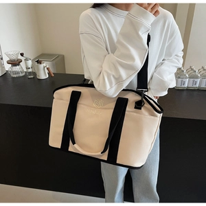 Detail of a beige canvas yoga bag with black straps worn by a model in a cafe setting