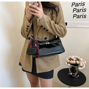 Detail of vintage black leather shoulder bag with gold buckle and mini pouch accessory