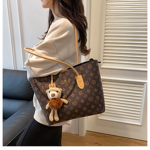 Close-up of vintage monogram tote bag with brown plush bear charm and large capacity