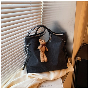 Close-up of black tote bag with thick fabric and a cute brown plush bear charm