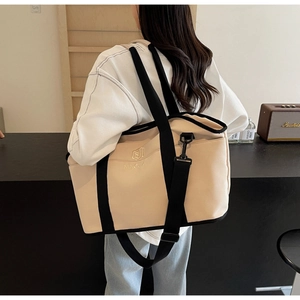 Rear view of a model carrying a beige yoga tote bag with black straps in a modern room