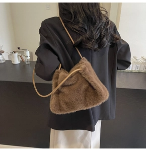 Detailed texture of brown faux fur shoulder bag with slender leather strap on model