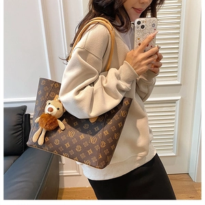 Classic brown monogram tote bag with cute bear charm shown on a female model shoulder