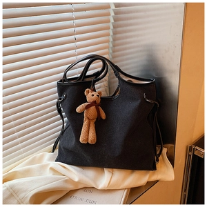 Close-up of large canvas tote bag with side buckle and cute brown bear charm