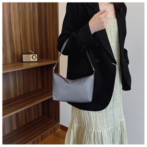 Detail showing grey shoulder bag with brown strap styled on a model in a suit