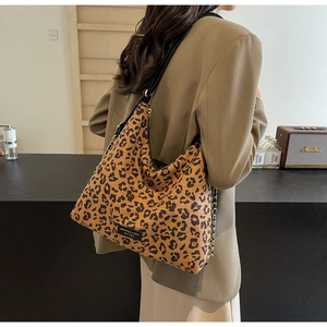 Detail of leopard print hobo bag with wide black strap and brand logo on canvas material