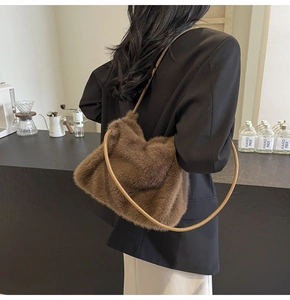 Close-up of a brown plush faux fur shoulder bag with leather strap on a cafe background