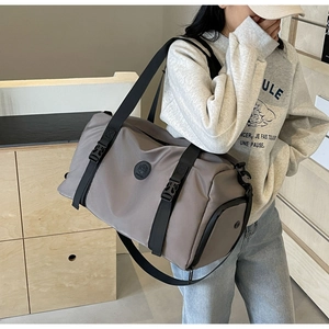 Detailed view of the taupe travel bag featuring black buckle straps and durable nylon fabric