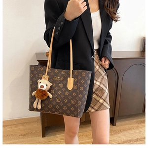 Detail of vintage brown tote bag with MQ pattern and knitted bear charm accessory