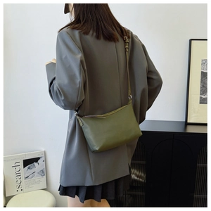 Modern dark green crescent leather bag shown on a model in a minimalist setting