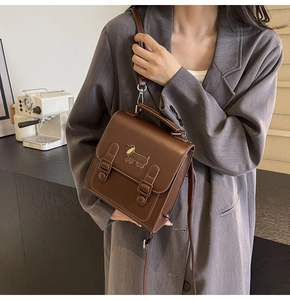 Détail d'un sac bandoulière marron vintage avec emblème de teckel en métal et rabat magnétique