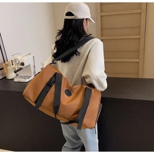 Brown travel bag with black shoulder strap shown on model in a minimalist cafe setting