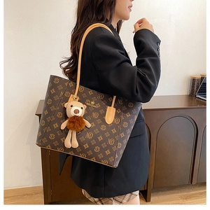 Detailed view of brown monogram tote bag with cute plush bear charm on shoulder strap