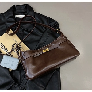 Detail of dark brown leather crossbody bag with gold twist lock and blue mini charm