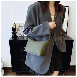 Olive green nylon crossbody bag shown worn with a gray blazer for a modern aesthetic