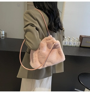 Pink plush shoulder bag with drawstring closure shown on shoulder in stylish indoor setting