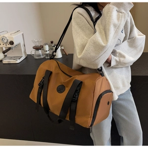 Brown travel bag with black shoulder strap shown in a modern lifestyle setting